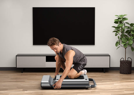 The man is folding up the Walking Pad.