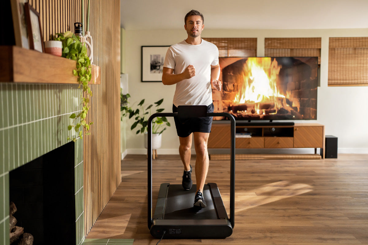 A man is running on a folding treadmill at home.