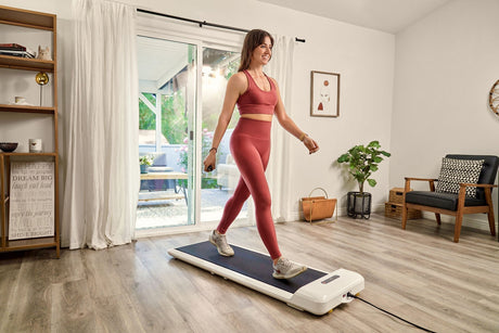 A woman in an orange yoga outfit is exercising on the indoor walking machines.