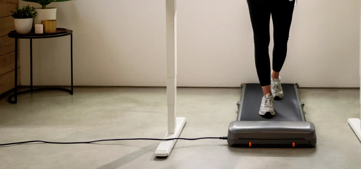 Power cord plugged into the treadmill under a standing desk